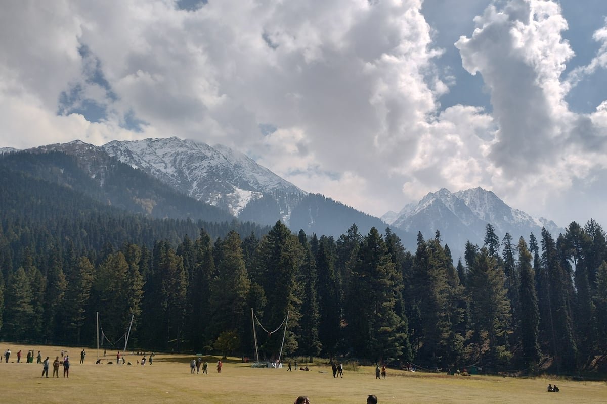 Baisaran Valley meadow known as Mini Switzerland surrounded by dense pine trees and mountains in Pahalgam