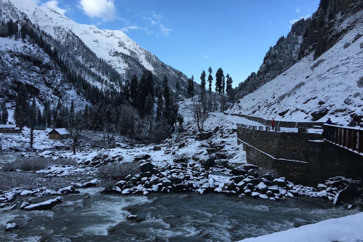 Scenic mountain landscape of Chandanwari covered in snow with gushing glacial river