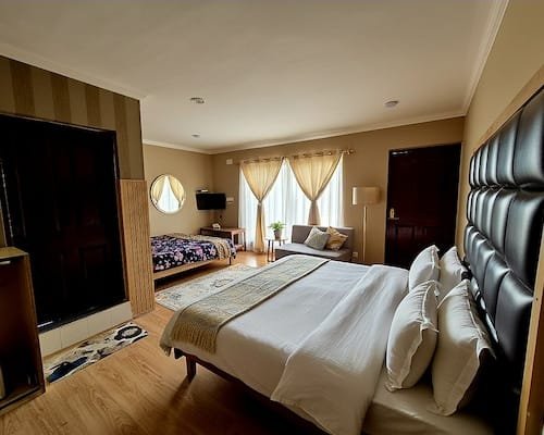 Bedroom interior featuring king bed with tufted headboard and daybed seating