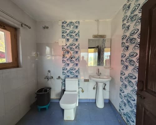 Clean en-suite bathroom with modern washbasin, shower fixtures, and tiled walls